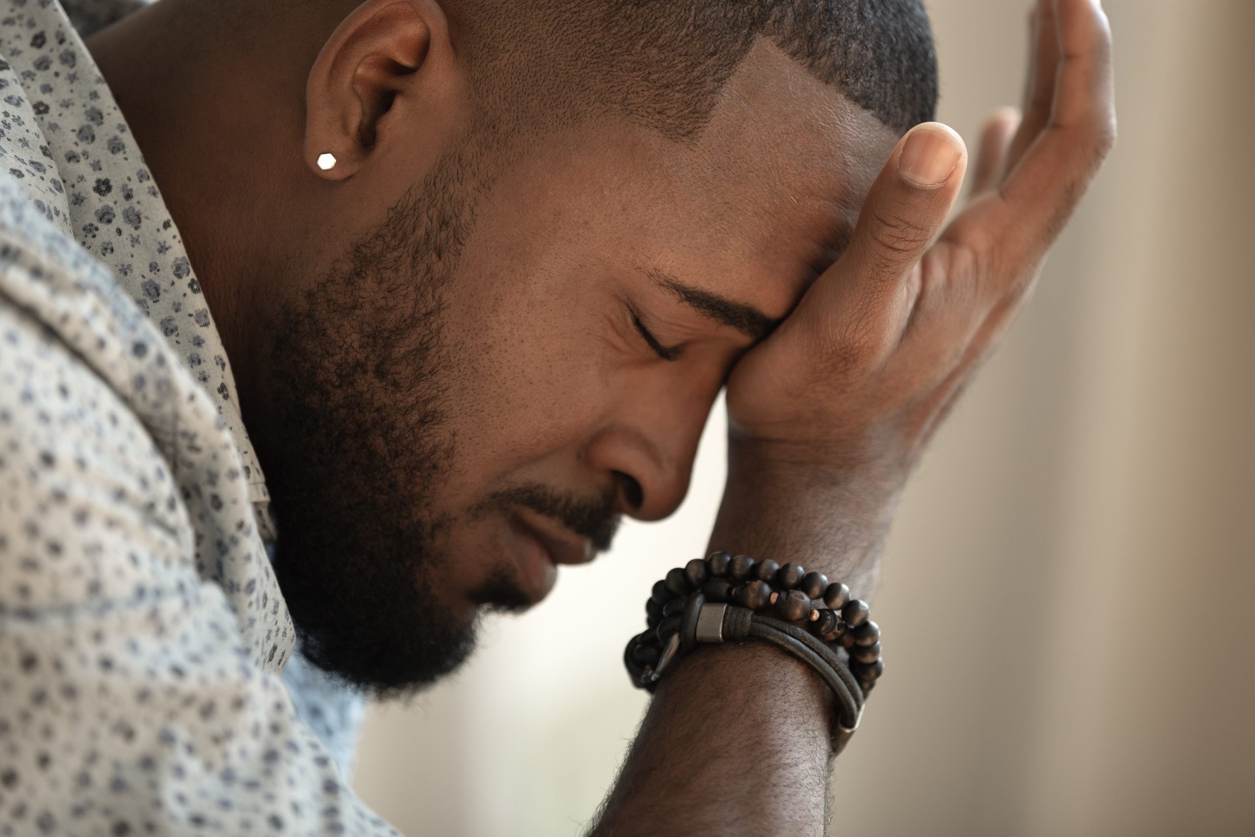 A man with his head down and hands on the forehead.