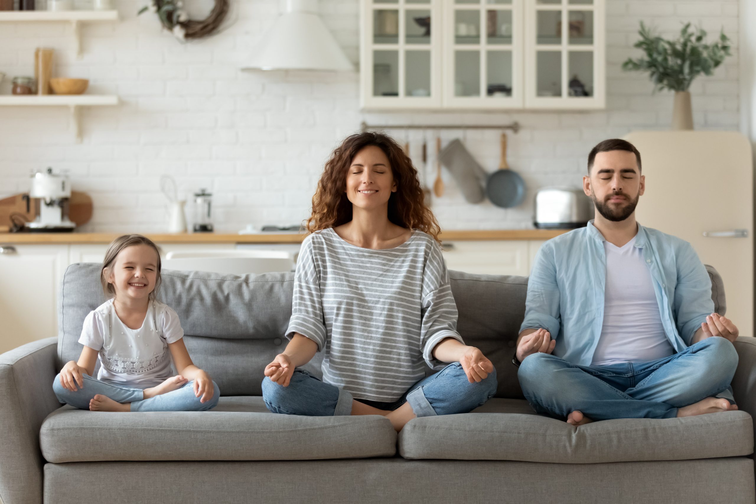 A family sitting on the couch doing yoga.